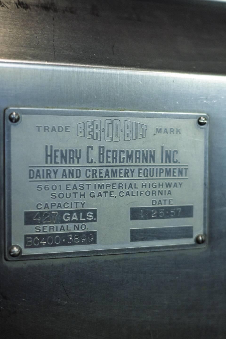 A metal equipment label for Henry C. Bergmann Inc. Dairy and Creamery Equipment showing capacity, date, and serial number details.
