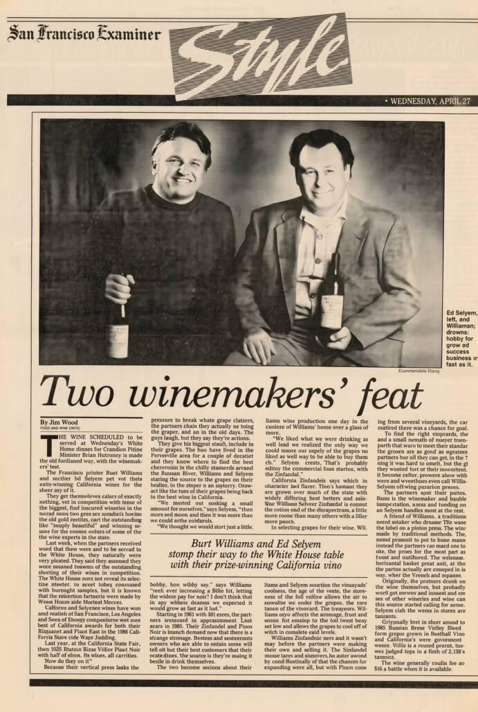 Two men stand side by side, each holding a wine bottle and smiling, in a newspaper feature titled "Two winemakers' feat" from the San Francisco Examiner.